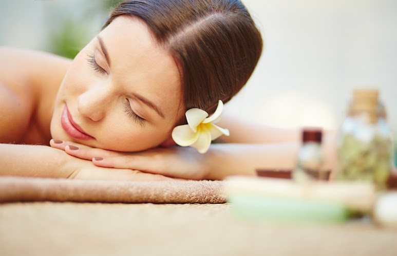 Relaxed female with frangipani flower in hair lying in spa salon