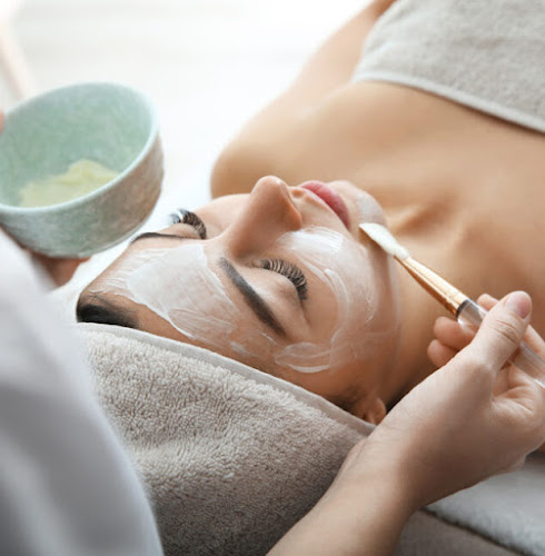 Cosmetologist applying mask on client's face in spa salon